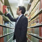 Hispanic businessman doing research in library